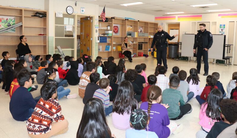 Officers from the Aurora Police Department speak to 2nd grade students.