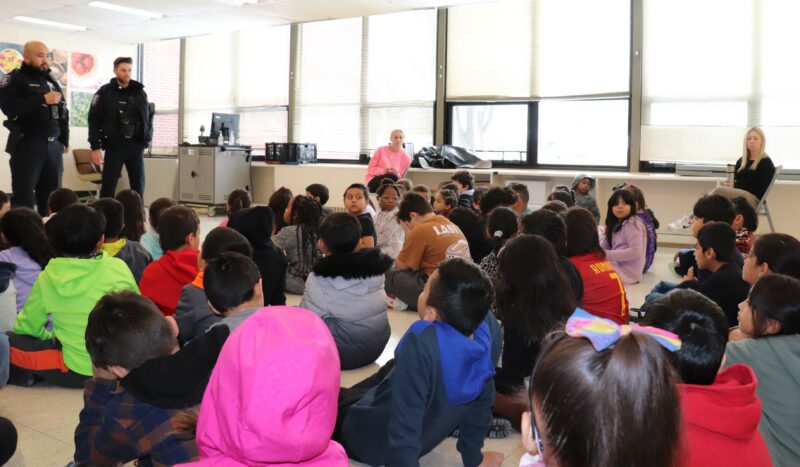 Officers from the Aurora Police Department speak to 2nd grade students.