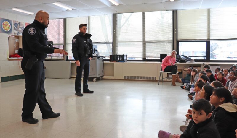 Officers from the Aurora Police Department speak to 2nd grade students.